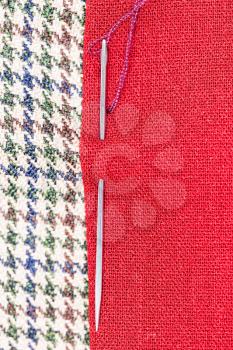 needle sews two pieces of fabric close up