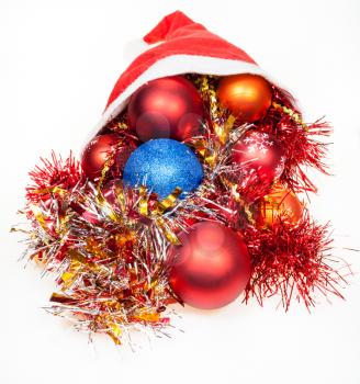 christmas gifts - xmas balls and decorations spill out from red santa hat on white background