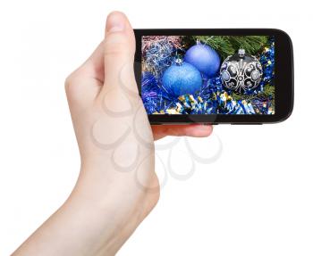 hand holds cellphone with Christmas decorations on screen isolated on white background