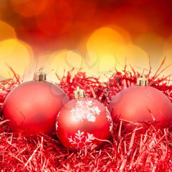 Xmas still life - red balls, tinsel with blurred red and yellow Christmas lights bokeh background