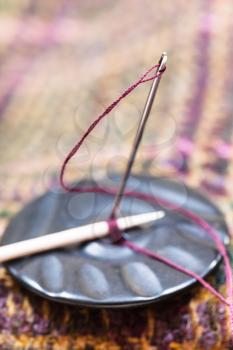 attaching of button to woolen material with stick by needle close up