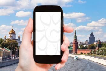 travel concept - hand holds smartphone with cut out screen and Moscow landscape on background