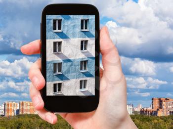 travel concept - tourist photographs picture of wall of urban house on smartphone