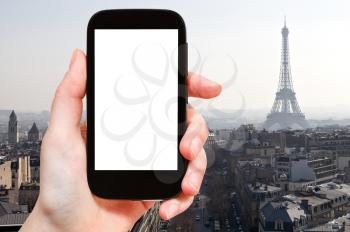 travel concept - hand holds smartphone with cut out screen and Eiffel tower and Paris district on background
