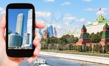travel concept - tourist photographs picture of Moscow City towers on smartphone