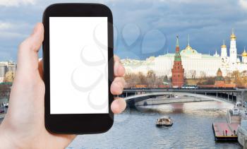 travel concept - hand holds smartphone with cut out screen and bridge and Moscow Kremlin on background