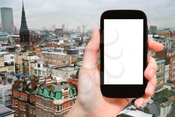 travel concept - hand holds smartphone with cut out screen and London skyline on background