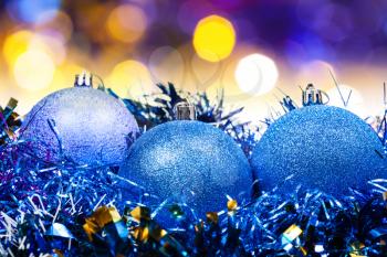 Xmas still life - blue balls, tinsel with blurred yellow and blue Christmas lights bokeh background
