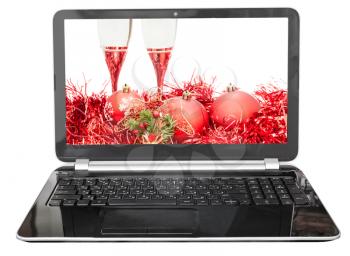 Christmas still life with red baubles and glasses on screen of laptop isolated on white background