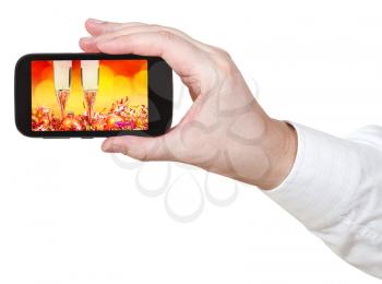 businessman holds smartphone with Christmas still life on screen isolated on white background