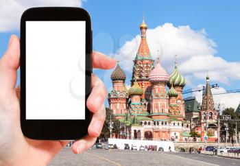 travel concept - hand holds smartphone with cut out screen and Saint Basil Cathedral on Moscoe Red Square on background