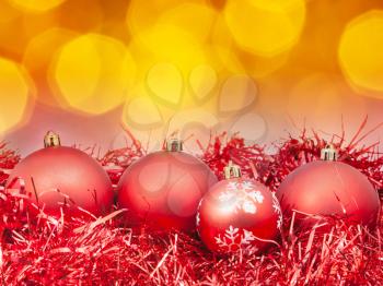 Xmas still life - red balls, tinsel with blurred orange Christmas lights bokeh background