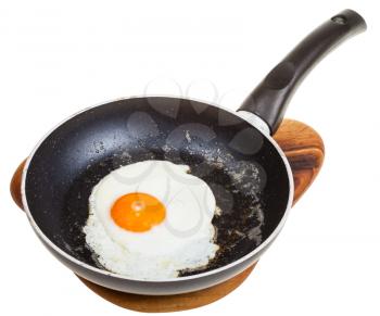 one fried egg in black frying pan isolated on white background