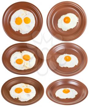set of brown ceramic plates with one and two fried eggs isolated on white background