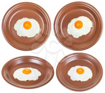 set of brown ceramic plates with one fried egg isolated on white background