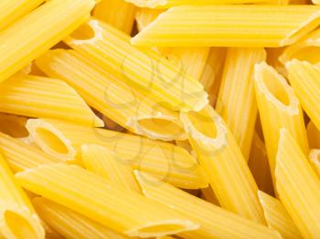 food background - durum wheat semolina pasta penne rigate close up