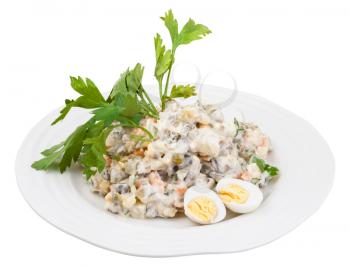 olivier russian salad with mayonnaise decorated with green parsley and boiled eggs on white plate isolated on white background