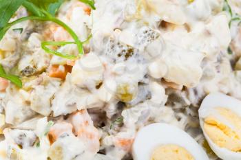 olivier russian salad with mayonnaise close up decorated with green parsley and boiled eggs