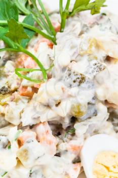 russian salad with mayonnaise close up decorated with greens and boiled eggs