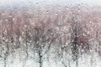 water drops from melting snow on home window glass in winter