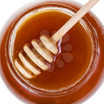 top view of wooden spoon on glass jar with brown honey isolated on white background