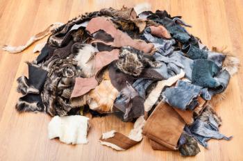 heap of scraps of leather and fur on wooden floor