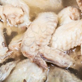 many boiled chicken wings in meat broth close up