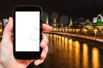 travel concept - tourist photographs Moscow night landscape with Kremlin and Moskva River on smartphone with cut out screen with blank place for advertising, Russia