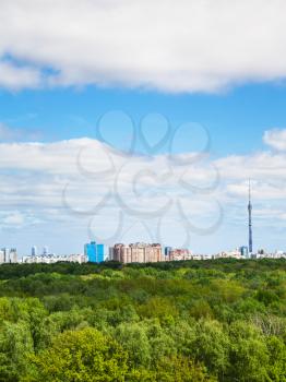 green forest and city on horizon under cloudy blue sky in summer day