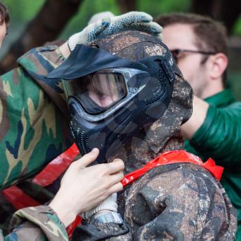 girl in camouflage wears protective mask for playing paintball