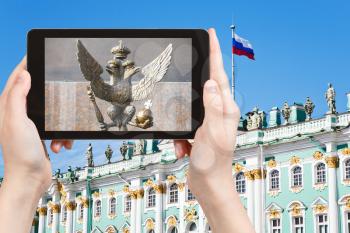 travel concept - tourist photographs Double-headed eagle symbol of Russian Empire near Winter Palace in Saint Petersburg, Russia on tablet pc