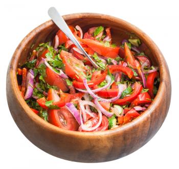 spoon in salad from fresh tomatoes, cucumbers, red onion seasoned by olive oil in wooden bowl isolated on white background