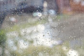 raindrops on windowpane and blurred urban street on background