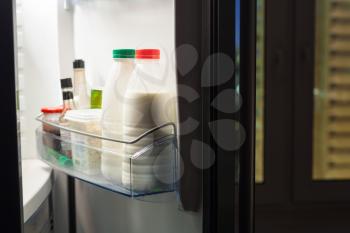 Open door of refrigerator with dairy products in night