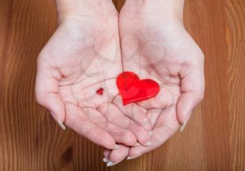 little and big hearts in female hands with wooden background