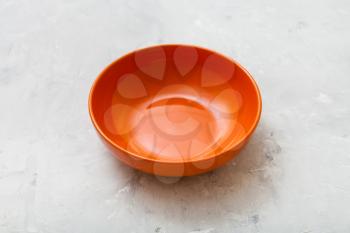 one orange bowl on gray concrete plate