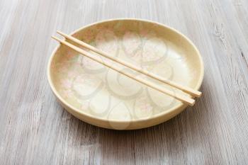 one yellow green plate with chopsticks on gray brown board