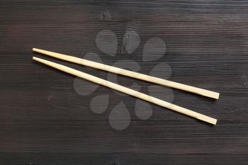 food concept - wooden disposable chopsticks ( waribashi ) on dark brown table