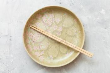 top view of one yellow green plate with chopsticks on gray concrete surface