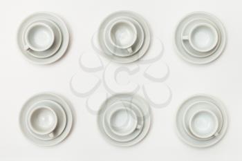 food concept - top view of six white cups and saucers on white background