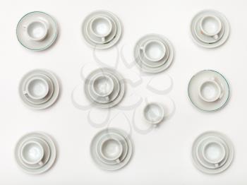 food concept - top view of many white cups and saucers on white background