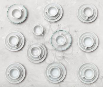 food concept - top view of many white cups and saucers on gray concrete board