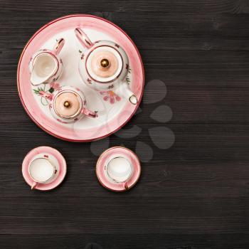 food concept - top view of pink porcelain tea set on dark brown board
