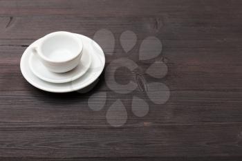 food concept - one white cup with saucers on dark brown table