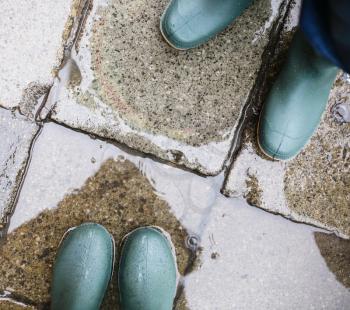 legs in green rubber boots in puddle in rainy day in Venice