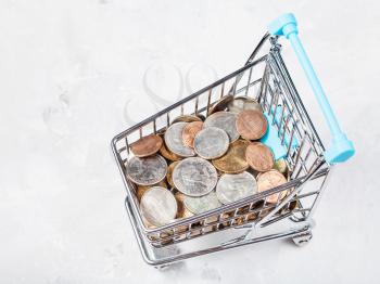 shopping cart with US coins on concrete plate