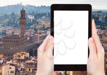 travel concept - tourist photographs skyline of Florence city with Palazzo Vecchio on tablet with cut out screen with blank place for advertising in Italy