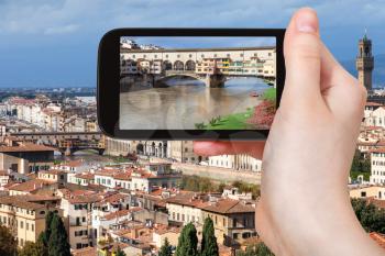 travel concept - tourist photographs Ponte Vecchio in Florence cityscape on smartphone in Italy