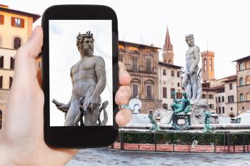 travel concept - tourist photographs sculpture of Neptune on piazza on signoria in Florence city on smartphone in Italy