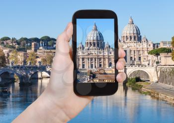 travel concept - tourist photographs St Peter basilica in Vatican from Rome city on smartphone in Italy